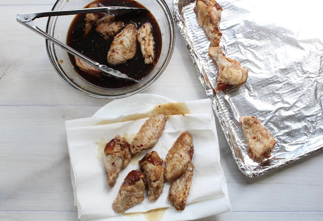 Bowl of marinade, plate of chicken wings, baking sheet with wings