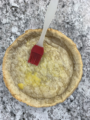 Egg wash being brushed onto blind baked pie crust