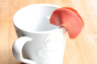 Image of fortune cookie draped over a cup
