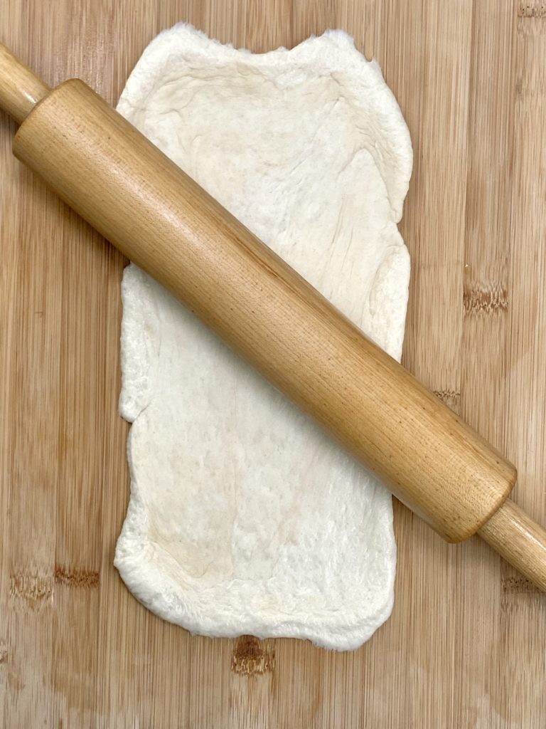 Pizza dough and rolling pin on a cutting board